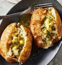 Air fryer baked potatoes with crispy golden skins and fluffy centers topped with butter, sour cream, and chives